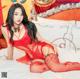 A woman in a red lingerie sitting on a bed.