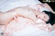 A woman laying on top of a bed in a pink dress.