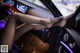 A woman sitting in the driver's seat of a car with her feet up.