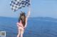 A woman holding a checkered flag on the beach.