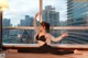 A woman in a black bra top and black leggings doing yoga in front of a window.