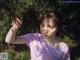 A young woman holding a pine tree branch in her hand.