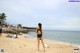 A woman in a black bathing suit standing on a beach.