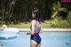 A woman in a blue and red swimsuit standing by a swimming pool.