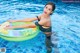 A woman in a black bikini sitting on an inflatable ring in a pool.