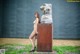 A naked woman standing next to a large metal sculpture.