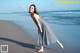 A woman in a black and white dress walking on the beach.