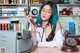 A woman with blue hair sitting at a desk holding a telephone.