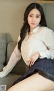 a woman sitting on top of a couch next to a pillow